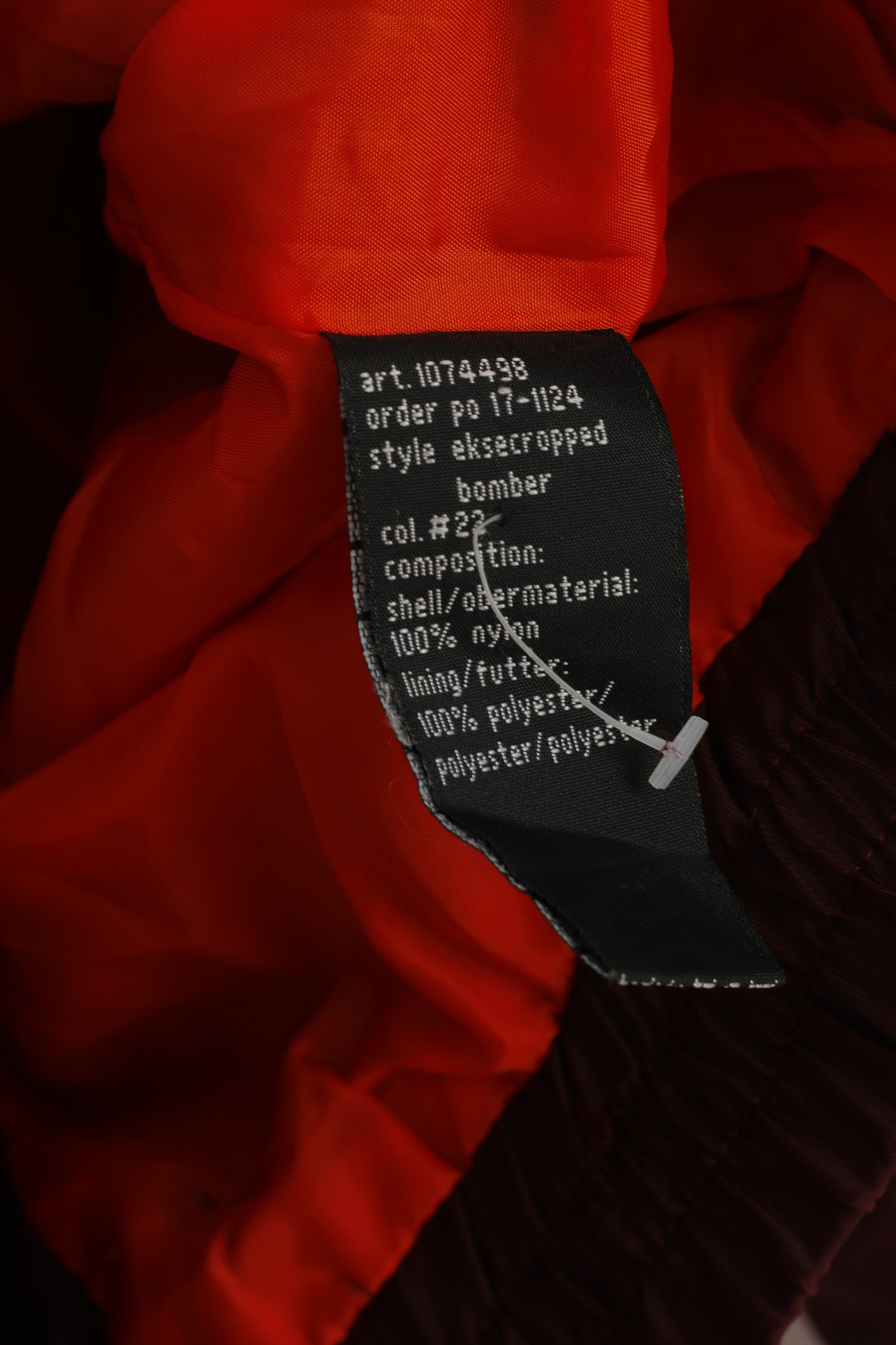 Close-up of a clothing tag on a red garment with visible text.