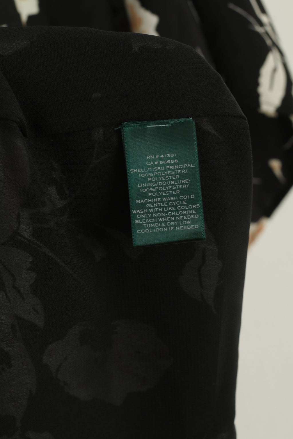 Black floral-patterned fabric with a green label on a white background
