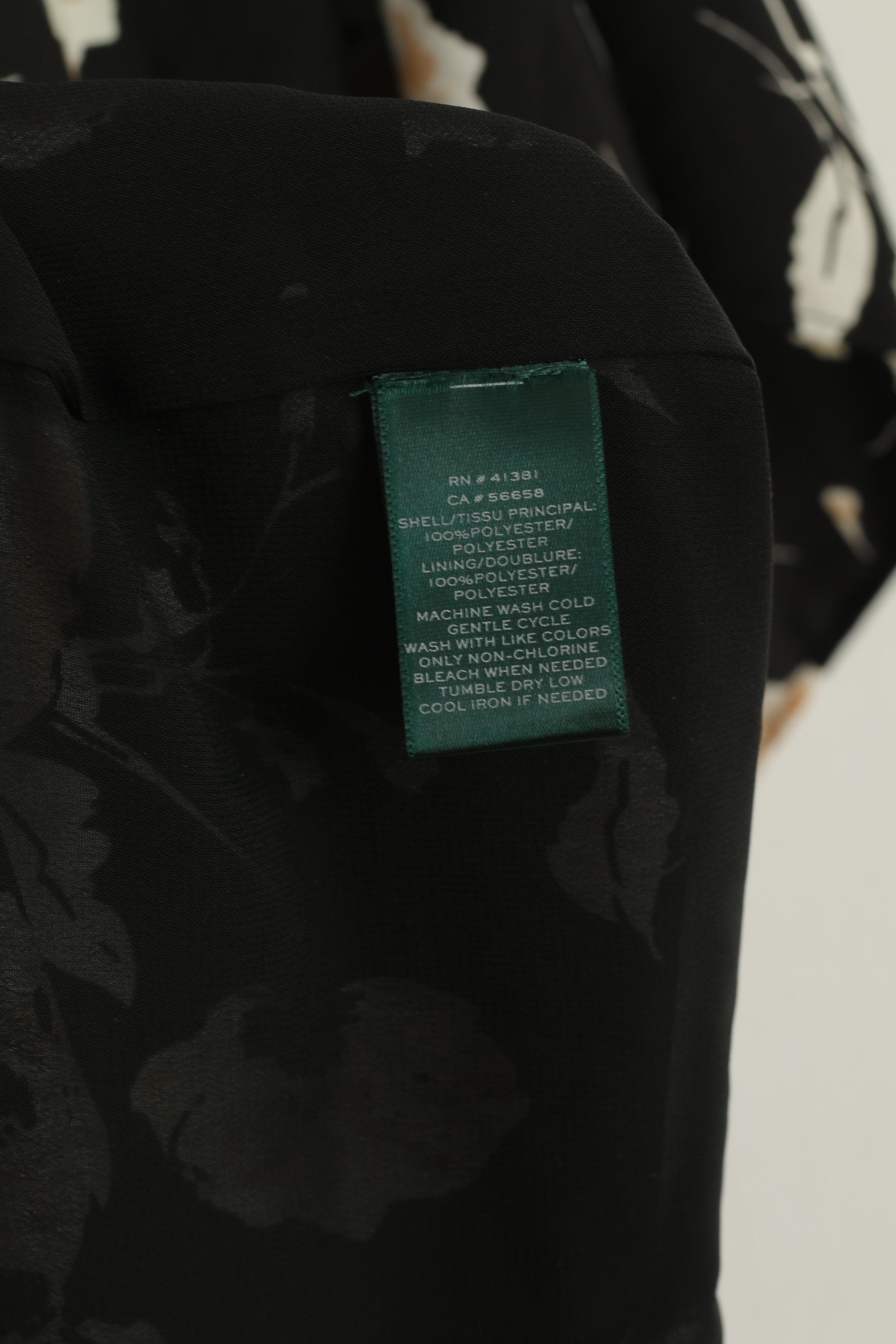 Black floral-patterned fabric with a green label on a white background